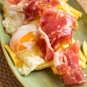 Fried eggs with potatoes and Iberian ham shoulder
